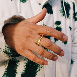 Close-up of gold chain-style band ring with vertical groove texture on male model