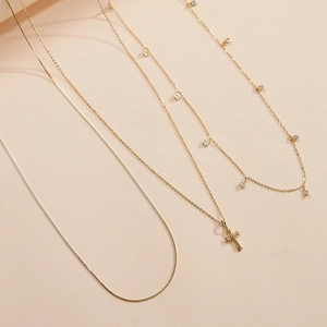 Detailed view of 3-piece gold cross pendant necklace set with round zircon accents