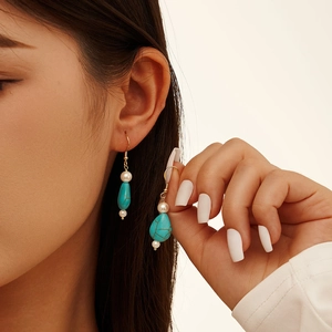 Bohemian gold drop earrings with turquoise stone and white pearls on a female model