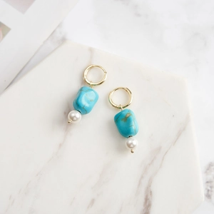 Détail de boucles d'oreilles turquoise avec perles sur surface en marbre
