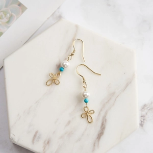 Detail of 925 silver gold drop earrings with pearl, blue bead and wire bow knot