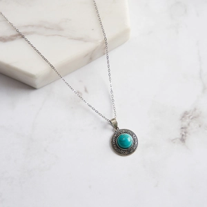 Gros plan du poinçon S925 et de la pierre turquoise sur le pendentif rond rétro