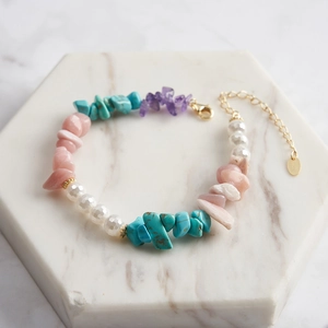 Detailed macro view of natural turquoise and amethyst beaded silver bracelet on marble stand