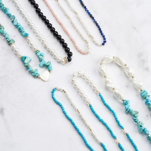 Elegant natural obsidian and turquoise beaded necklaces on white marble background