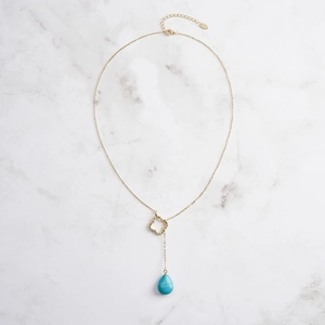 Detailed close-up of a gold clover charm and turquoise teardrop on 925 silver necklace