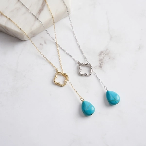 Detailed view of teardrop turquoise pendants on gold and silver clover necklaces