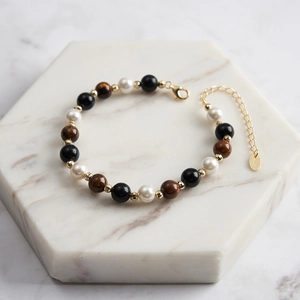 Detail of S925 silver bracelet with tiger eye stone, pearl, and black agate beads