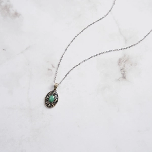 Detail of S925 sterling silver necklace with green turquoise stone and vintage floral engraving