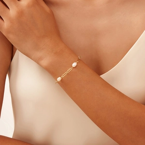 Elegant 18K gold paperclip chain bracelet with natural pearls worn by a model