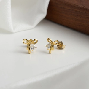 Detail of S925 sterling silver bow earrings with sparkling teardrop zircon in 14K gold