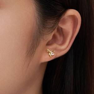 Elegant gold bow earrings with pear-cut zircon stone worn by a female model