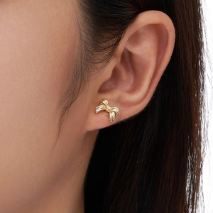 Polished gold ribbon bow earrings made of S925 sterling silver worn by a model