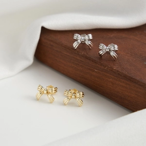Elegant gold and silver S925 sterling silver bow knot stud earrings on display