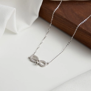 Vue détaillée du pendentif infini en argent et oxydes de zirconium sur tissu de soie blanc