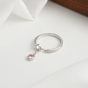 Detailed close-up of S925 sterling silver ring with a pink heart zircon pendant on fabric