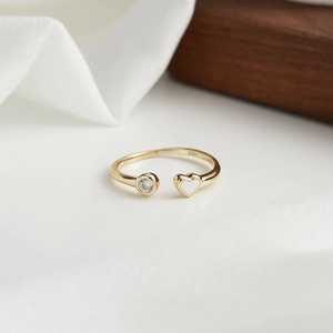 Détail d'une bague en argent S925 doré avec zircon rond et élément en forme de cœur blanc
