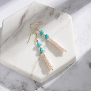 Bohemian drop earrings with natural turquoise beads and baroque pearls on marble surface