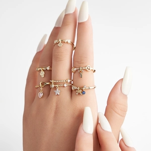 Stacked gold rings on fingers featuring colorful zircon charms like hearts and stars
