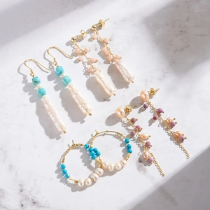 Bohemian earrings set with natural turquoise and baroque pearls on white marble surface