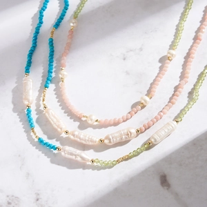 Close-up of Baroque pearls and natural stone beaded necklaces on white marble
