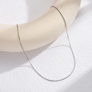 Detailed view of a silver Chopin chain necklace wrapped around white art decor