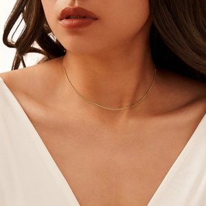 Minimalist gold Chopin chain necklace worn by a model in a close-up portrait view