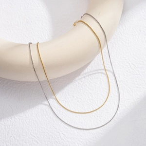 Minimalist Chopin chain necklaces in gold and silver hanging on a U-shaped display