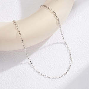 Detail of a sleek S925 sterling silver paperclip chain necklace on a ceramic stand