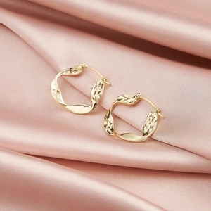 Detailed close-up of gold-plated S925 sterling silver hoop earrings with wavy texture