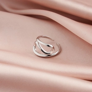 Nahaufnahme der geflochtenen S925 Silber Ringe auf rosa Seidenstoff Hintergrund