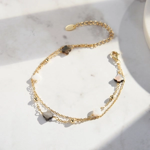 Double-layered gold chain bracelet with white and black shell clover motifs and beads