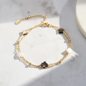 Detailed macro view of a gold-layered S925 silver bracelet with black and white clover charms