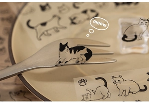 Macro shot of cute hand-drawn cat sticker on a stainless steel fork for scrapbooking