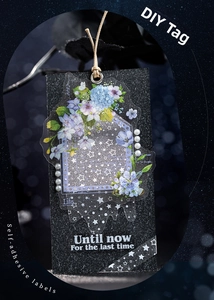 Detail showing a DIY black matte gift tag decorated with purple floral starry stickers