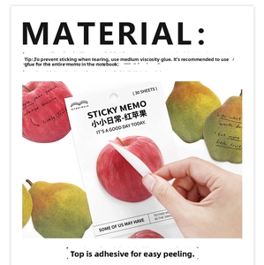 Detail of red apple shaped sticky notes showing adhesive strip and paper texture on desk