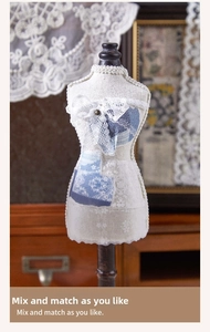 Close-up of vintage mini dress form sticker with lace detail and blue floral fabric