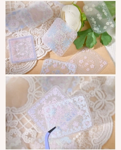 Detailed macro view showing delicate lace floral PET stickers and craft tweezers on lace fabric