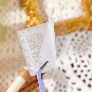 Detailed close-up of vintage white lace PET stickers being applied with tweezers for DIY