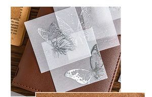 Detail of translucent silver foil butterfly stickers on a vintage leather journal