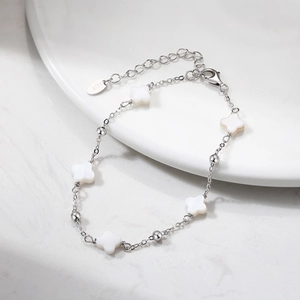 Detalle macro de la pulsera de plata S925 con colgantes de trébol en concha blanca