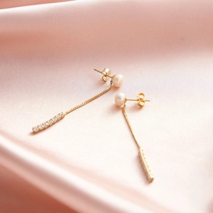 Elegant gold long tassel drop earrings with white pearls and sparkling zircons on pink silk