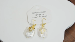 Détail de boucles d'oreilles perles et croix avec crochets en argent 925 sur carte