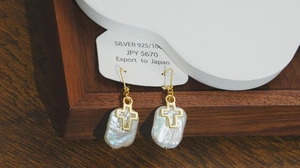 Détail de boucles d'oreilles perles baroques avec croix dorée sur crochets argent 925