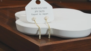 Detail of S925 sterling silver gold earrings with white pearls and sparkling diamond tassels