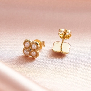 Vue macro de boucles d'oreilles trèfle en argent S925 avec perles et pierres blanches