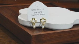 Détail des boucles d'oreilles croix en argent S925 avec perles naturelles blanches et ciselures