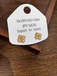 Gros plan de boucles d'oreilles trèfle en argent S925 avec perles et zircon sur bois