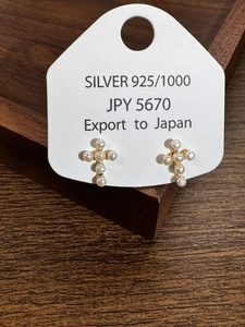 Macro detail of gold S925 sterling silver cross earrings with round white pearls