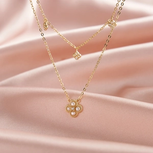 Collier double rang en or avec pendentifs trèfle en perles sur fond de soie rose élégant