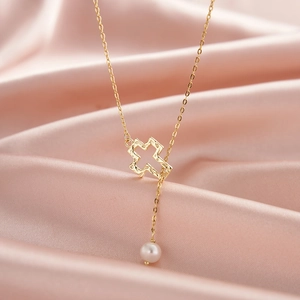 Collier élégant avec croix dorée et perle sur fond de satin rose avec chaîne en forme de Y